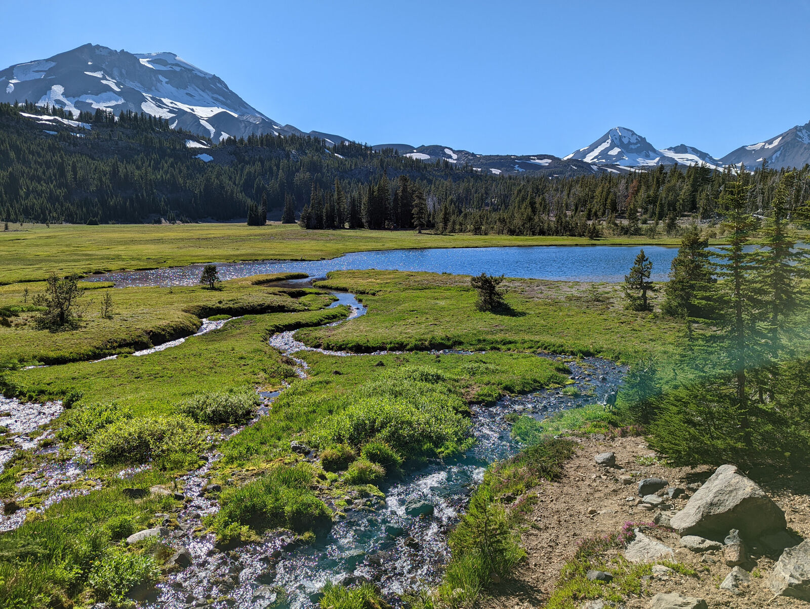 Mountain meadow and stream under snowy Cascades peaks in Central Oregon